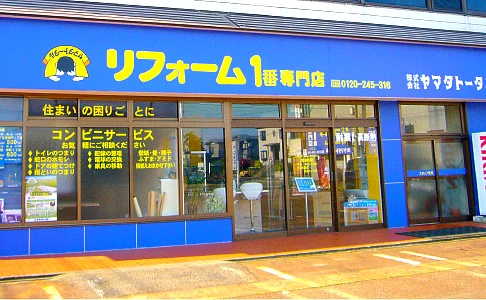 ヤマダトータル店舗写真。青色の建物です。お店の前に駐車場スペースがございます。